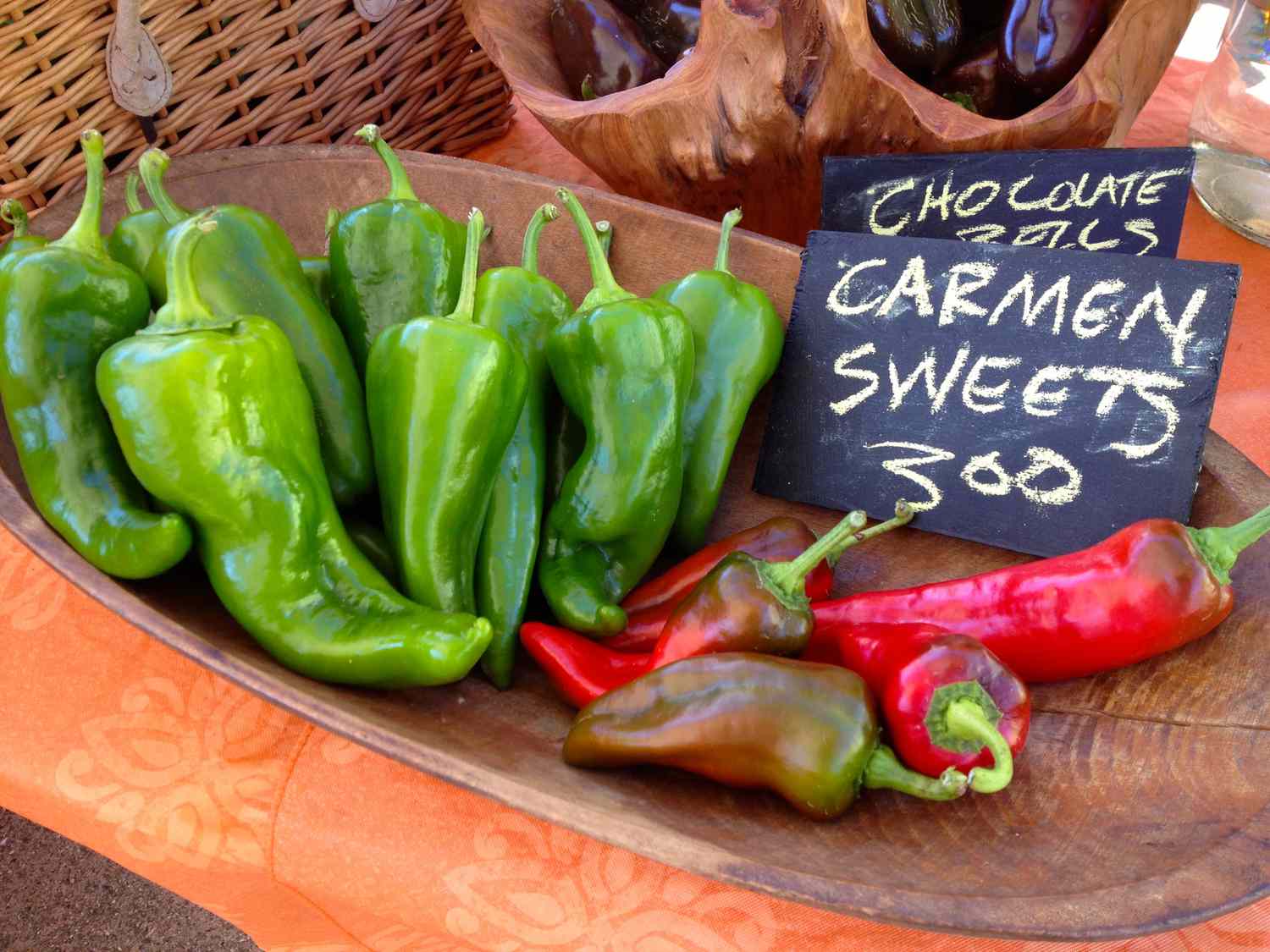 poivrons rouges et verts de Carmen avec un signe à la craie dans un bol en bois sur une table de marché