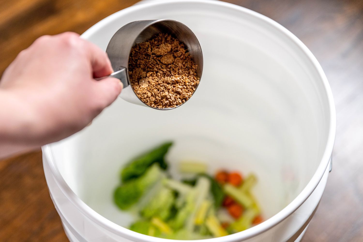 Déchets végétaux et inoculant bokashi versés dans le seau