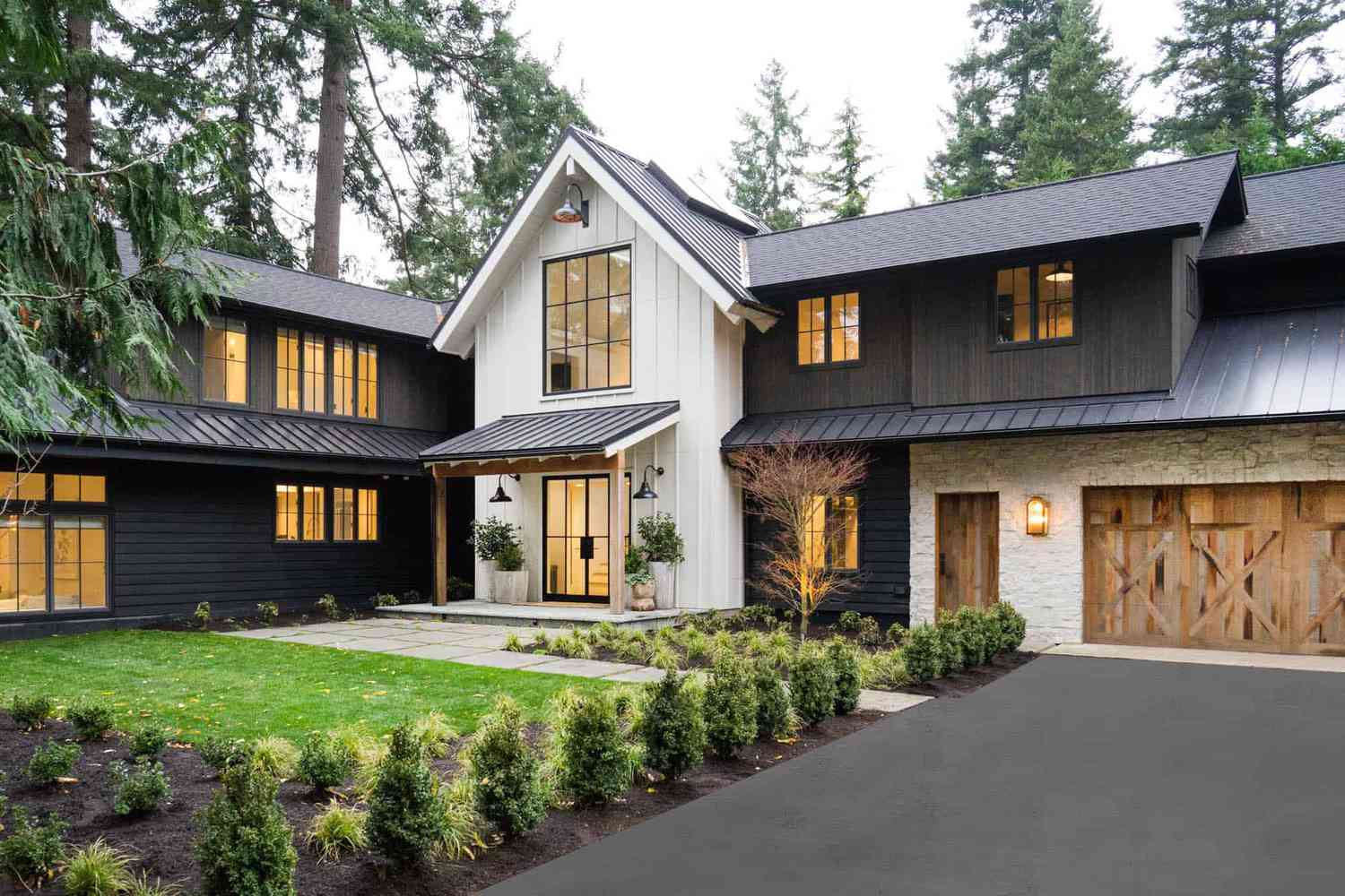 Maison extérieure avec porte de garage en bois et joli aménagement paysager.