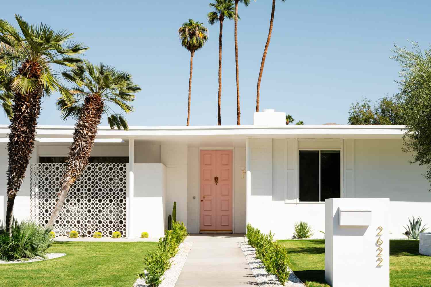 Une maison blanche avec une porte d'entrée rose vif