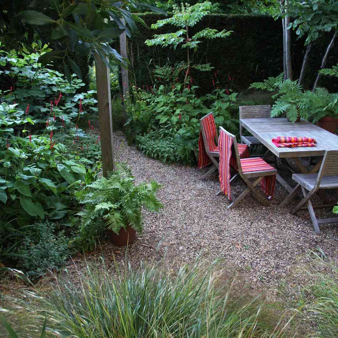 Terrasse en gravier entourée de plantes avec table