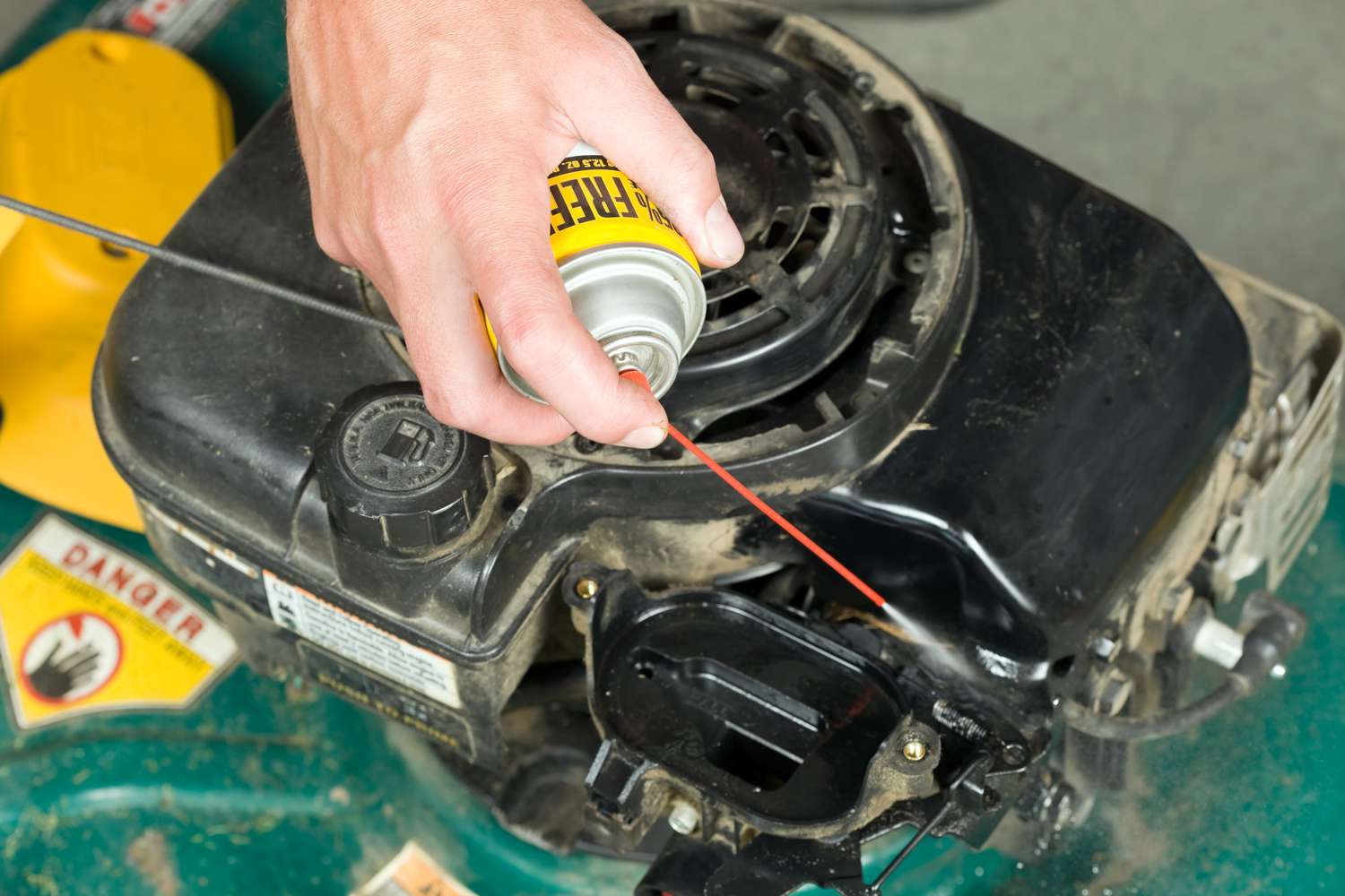 personne nettoyant le carburateur d'une tondeuse à gazon